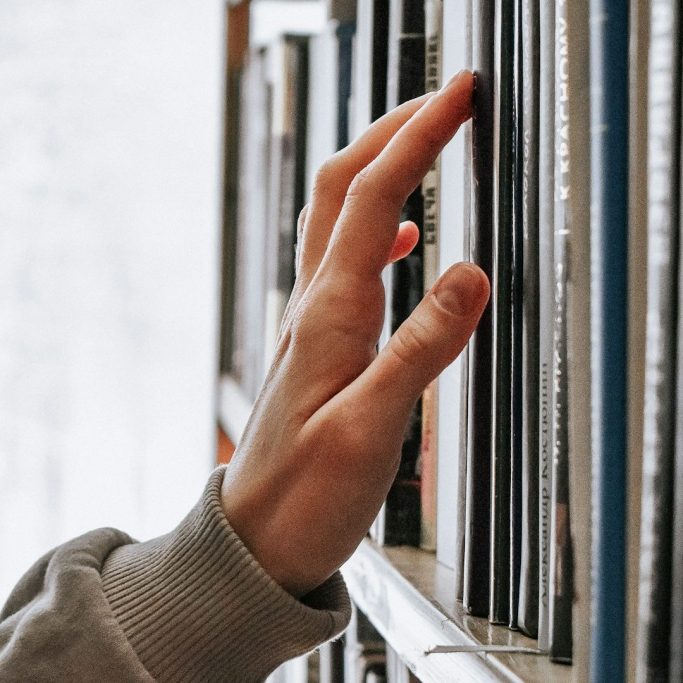Mano eligiendo un libro en una estantería
